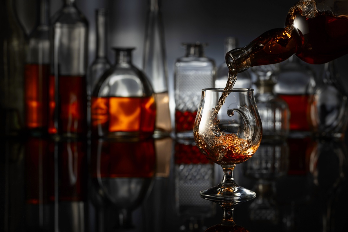 brandy poured from bottle into a snifter other brandy bottles and glasses in the background