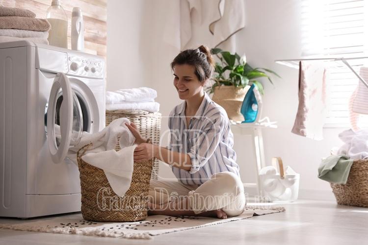 young,woman,taking,laundry,out,of,washing,machine,at,home