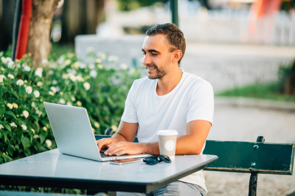 business on fresh air. confident young man working on laptop while sitting at the table outdoors