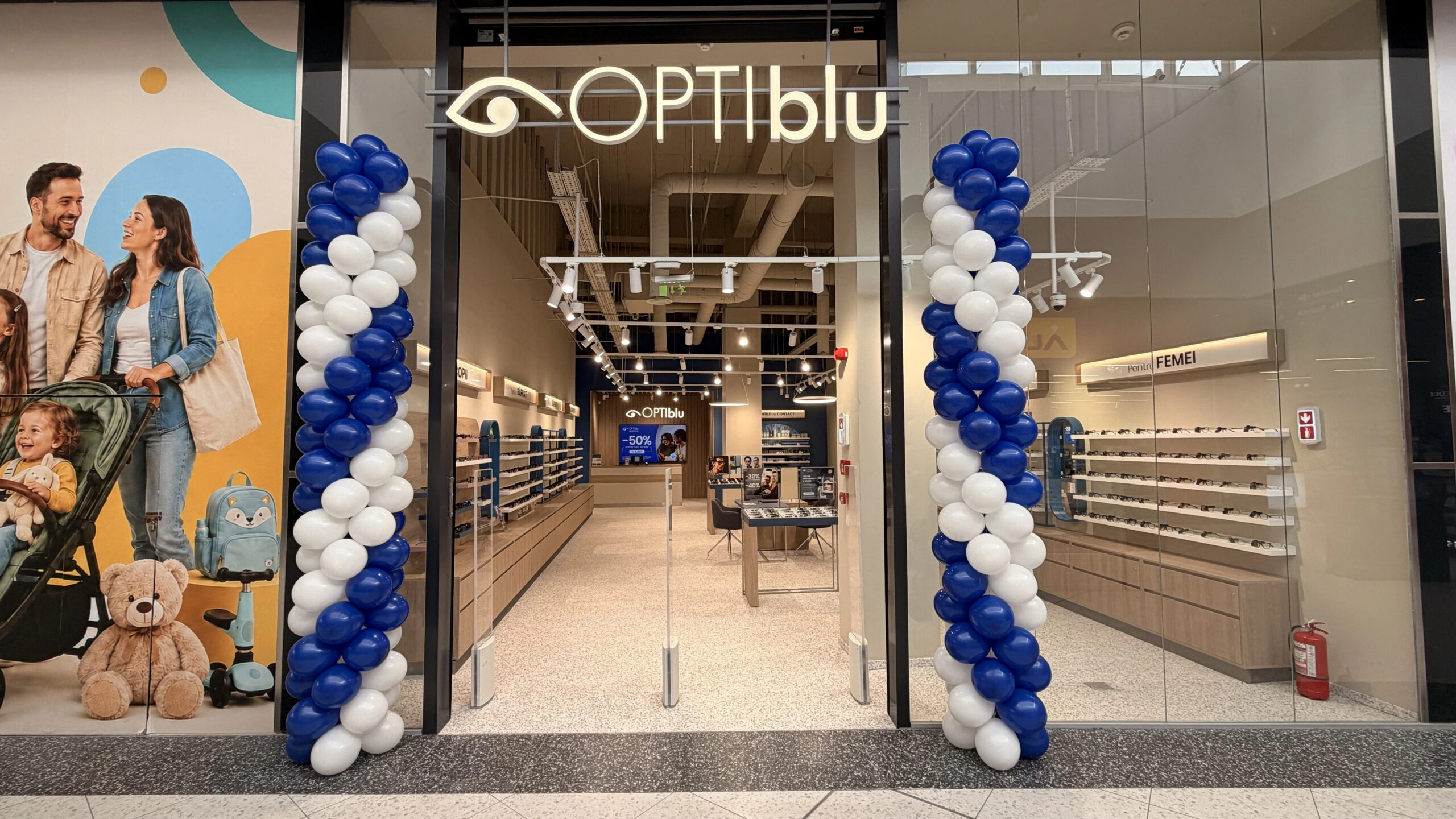 Intrarea în magazinul OPTIblu din Târgoviște, decorată cu baloane albe și albastre la deschidere.